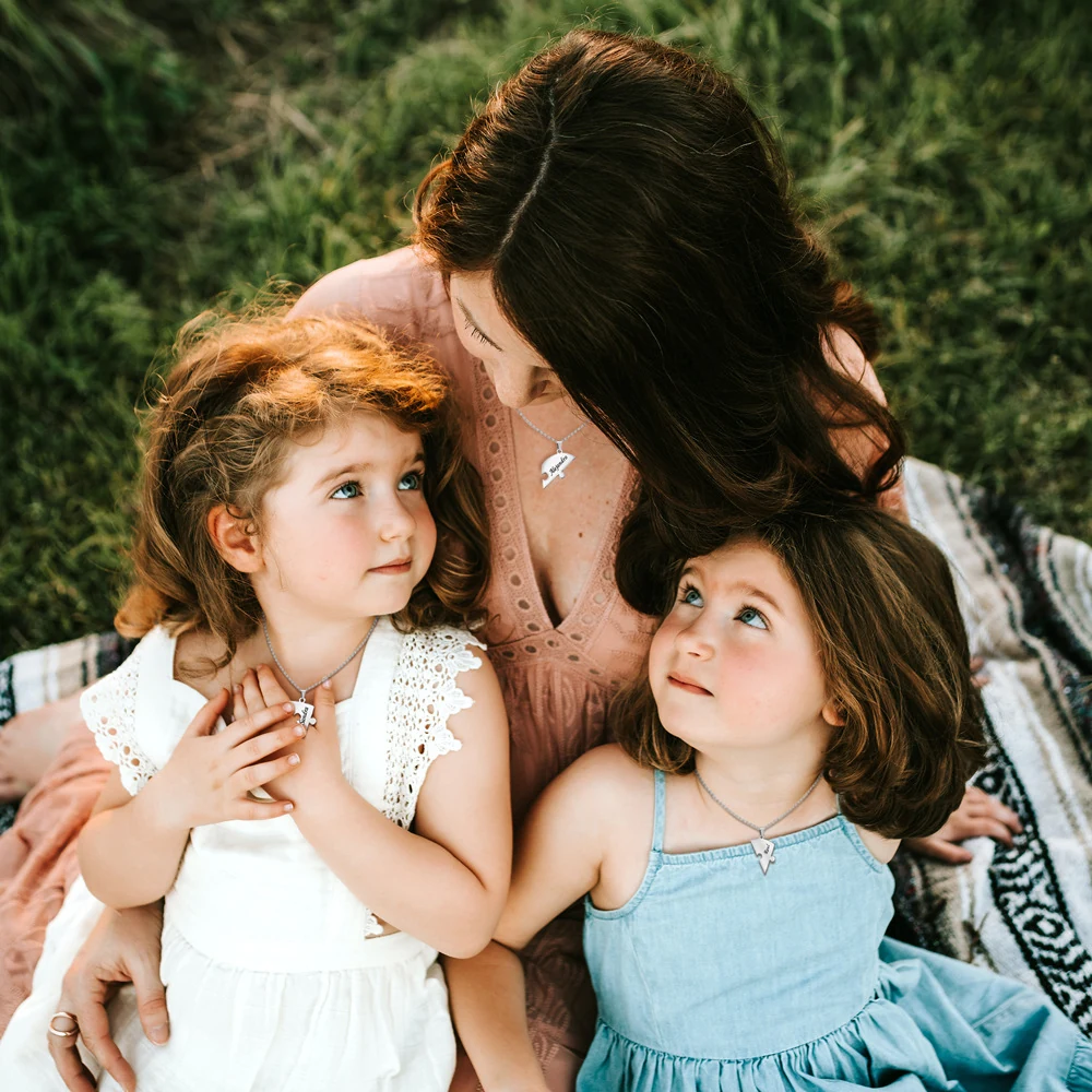 Mother and two daughters wearing separate engraved pieces from a shared Together Heart Puzzle Necklace set